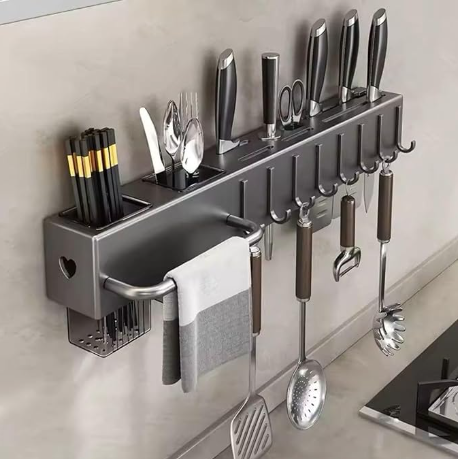Suporte organizador de parede em aço inox com facas, conchas e pano de prato pendurados para liberar a bancada da cozinha.