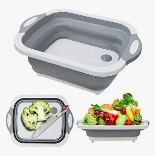 Tábua de corte e cesto escorredor dobrável 3 em 1 cinza, aberta e encaixada sobre a cuba da pia para lavar legumes.